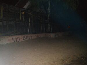 overview picture of the front of the aviary at night, with the graffiti on the bottom saying "Jij bent toch ook liever vrij?"